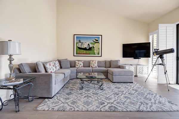 Sink into plush gray sectional seating in your spacious living room, where soft natural light and comfortable furnishings invite you to unwind after a day of adventure.